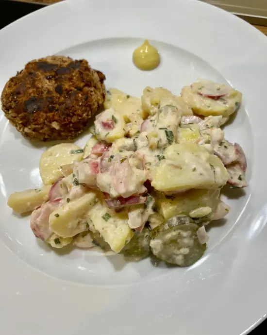 Ein Teller voll mit Kartoffelsalat, einer Bulette und einem klecks Senf